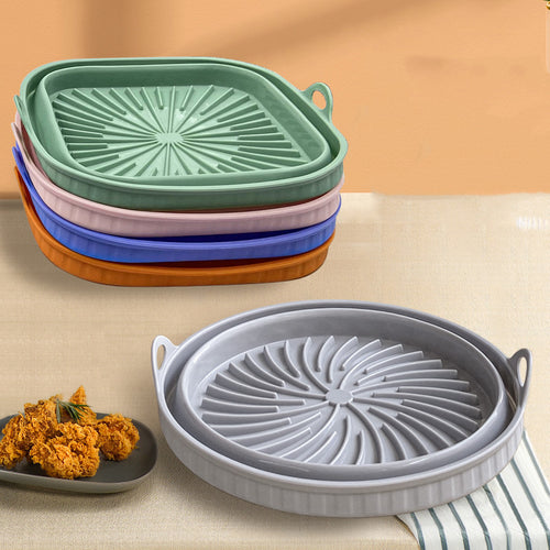 Air Fryer Silicone Pot in various colors stacked on a table with a dish of fried food beside.